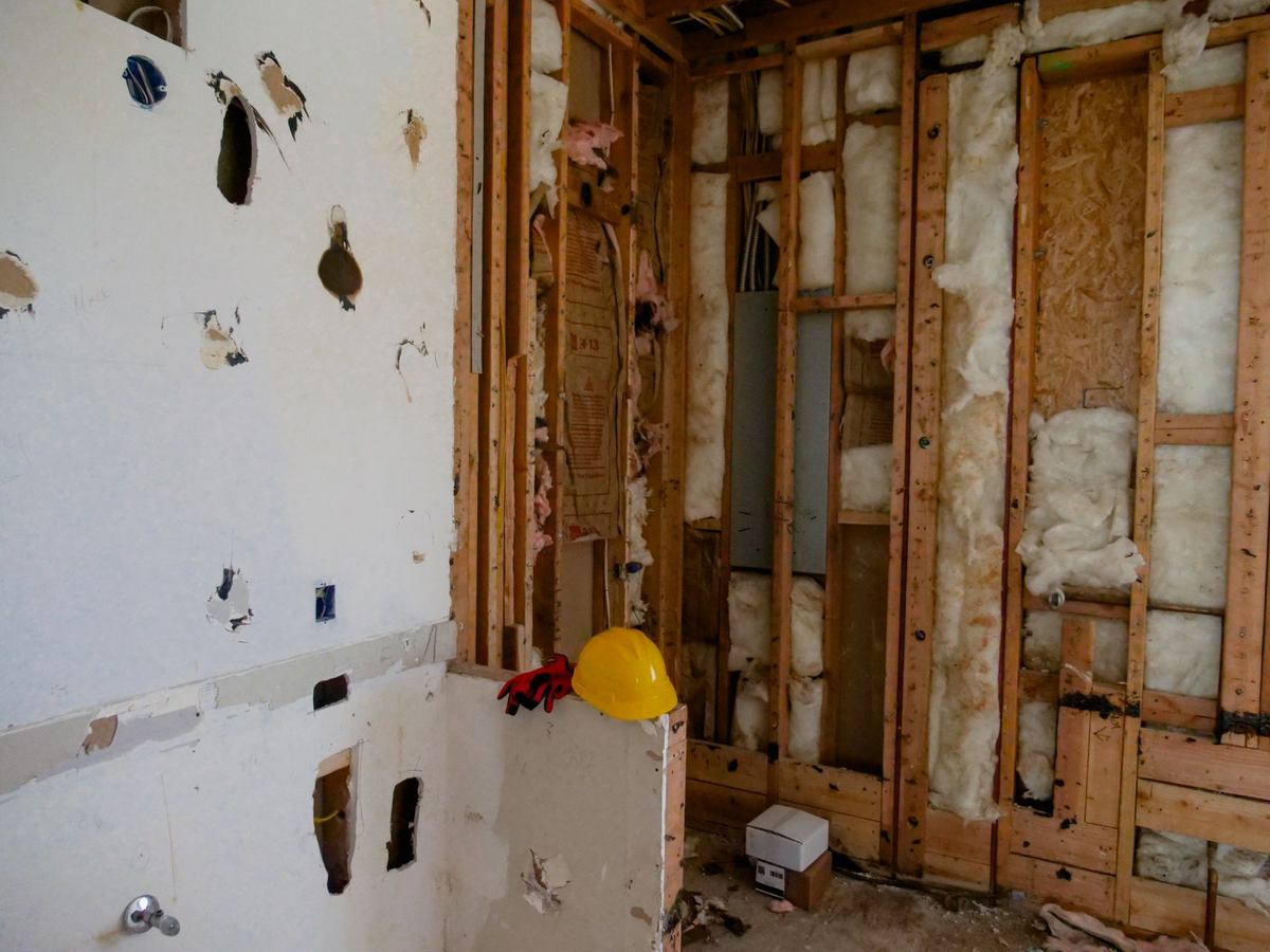 Gutted room mid remodel with drywall removed and exposed wall studs and insulation